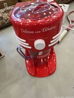 Front view of red Nostalgia Coca-Cola frozen drink maker with attached pitcher