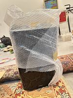 Onkyo black subwoofer wrapped in bubble wrap placed on rug