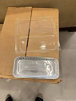 Opened carton showing stacked aluminum loaf pans with attached clear lids