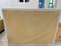 Rear view of queen size box spring foundation showing beige fabric panel and white trim