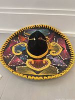 Top view of black velvet sombrero showing full multicolor embroidered design and yellow braided edging