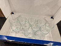 Open box showing twelve clear glass mugs