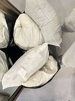 Group of four standard pillows, showing two striped and two solid white, piled together