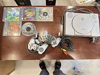 Top view showing console, controllers, cables, five cased games and one loose disc