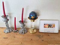Group shot showing two silver grape-motif holders with red tapers, brass/glass pillar holder with mosaic globe, and boxed LED candles