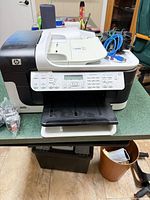 Front view of HP Officejet 6500 printer with tray extended and cables on top