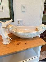 Whale figurine beside matching oval bowl on shelf