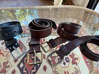 Four leather belts laid out showing colors and buckles