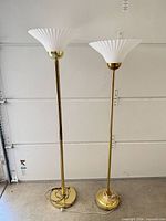 Full view of both brass-finish torchiere floor lamps with cords on floor