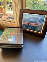 Mahogany-finish frame with sunset photo next to stack of sealed black Format frames