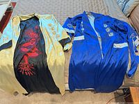 Gold robe with dragon embroidery and blue robe side by side on bed