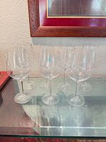Seven crystal Burgundy wine glasses lined on glass surface