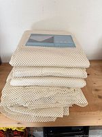 Stack of folded beige PVC mesh rug pads with product card on top