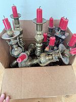 Box of assorted brass candlesticks with red candles