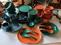 overhead view of full set showing plates, bowls, cups, platters, utensils in green and orange