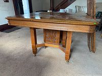 Oak dining table showing pedestal base and casters