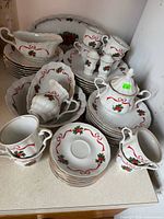 All pieces stacked on countertop including platter, plates, cups, serve pieces