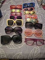 Full layout of 14 assorted sunglasses on table