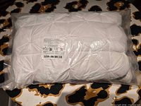Sealed white quilted pillow in clear plastic bag