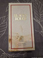 Front of Le Aura Rouge box showing gold foil title, red border, staining at lower left