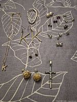 All items laid out showing necklace, bracelet, cross pendant and multiple earring pairs