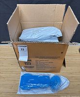 Master carton open showing sealed Shimmy Scrub packages and one blue scrub pad with brush