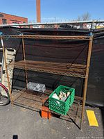front view of rusted 3-tier metal shelving with additional items on shelves