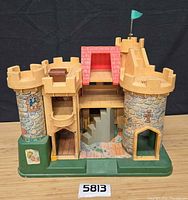 Front view of Fisher-Price castle showing towers, drawbridge, roof, base and chest