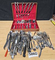 Flatware chest open with Checkered Frost set and large pile of assorted flatware