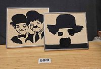 Two framed needlepoint artworks side by side on table