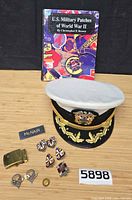 Overview of all items including cap, book, insignia, buckle, name badge