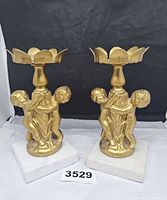 Full view of both gold-tone cherub candle holders on marble bases