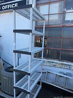 Full view of white plastic 6-tier shelving unit placed outdoors