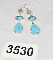 Front view of sterling silver three-stone dangle earrings on white background