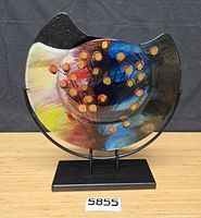 Front view of multicolour abstract art glass vase on metal stand