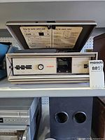 Projector in case, lid open showing control panel and remote