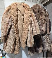 Two fur coats hanging side by side