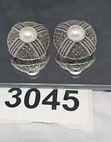 front view of both dome earrings on mirror showing marcasite and pearl centers