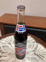 Front view of sealed Pepsi-Cola commemorative bottle showing 1975 World Champions text and Reds mascot graphic