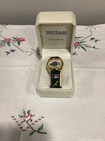 Watch in open presentation box showing bezel, dial graphics, strap, and box inscription