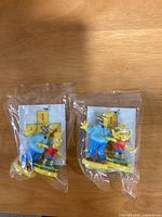 Two sealed Kellogg’s 2003 Homer and Bart Simpson skateboard figurines in cellophane with cardboard insert