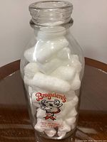 Front view of clear glass Broguiere’s milk bottle showing cartoon cow logo