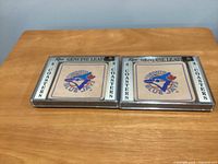 Two unopened plastic cases each holding four leather Toronto Blue Jays coasters