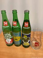 Front view of three commemorative bottles and inverted glass