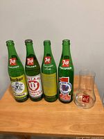 Front view of four 7up NCAA bottles and upside-down glass