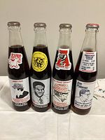 Front view of all four commemorative Coke bottles showing coach portraits and logos