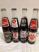 Front view of four sealed commemorative Coca-Cola bottles showing team logos and championship text