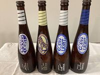 Front view of four baseball bat-shaped Coors Signature Series bottles showing labels and neck stripes