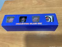 Front view of boxed set showing four Detroit Red Wings logo shot glasses through window openings