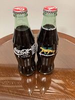 Two of the sealed 8 oz University of Vermont Catamounts Coca-Cola bottles showing Coca-Cola logo and commemorative graphics